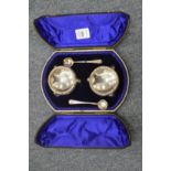 A cased pair of circular silver salts with spoons.