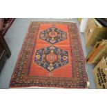 A Persian design rug, red ground with two large central medallions, 158cm x 128cm.