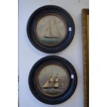 A pair of colour oiliographic prints depicting sailing ships in circular ebonised frames.