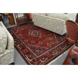 A large Persian design carpet, red ground with stylised decoration, 300cm x 222cm.