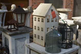 A terrarium, a metal house shaped candle holder and other similar items.