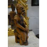 A tribal carved wood seated male figure.