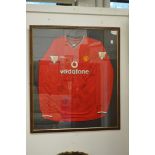 A Manchester United football shirt, signed and framed and glazed.