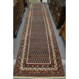 A Persian runner or hall carpet, decorated with stylised Boteh design, 450cm x 110cm.