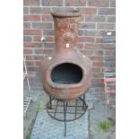 A chiminea with wrought iron stand.