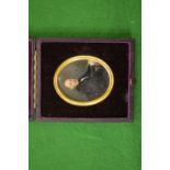 A portrait miniature of a Gentleman seated at a desk in a leather case.