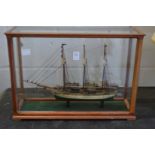 A good small model of a three masted sailing ship in a glass display case.