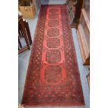 A Persian style runner, red ground with seven large motifs, 290cm x 80cm.