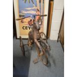 A carved wood and wrought iron hobby horse style tricycle.
