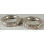 A PAIR OF ISLAMIC SILVER BANGLES, with embossed decoration, weight 130g (including beads inside
