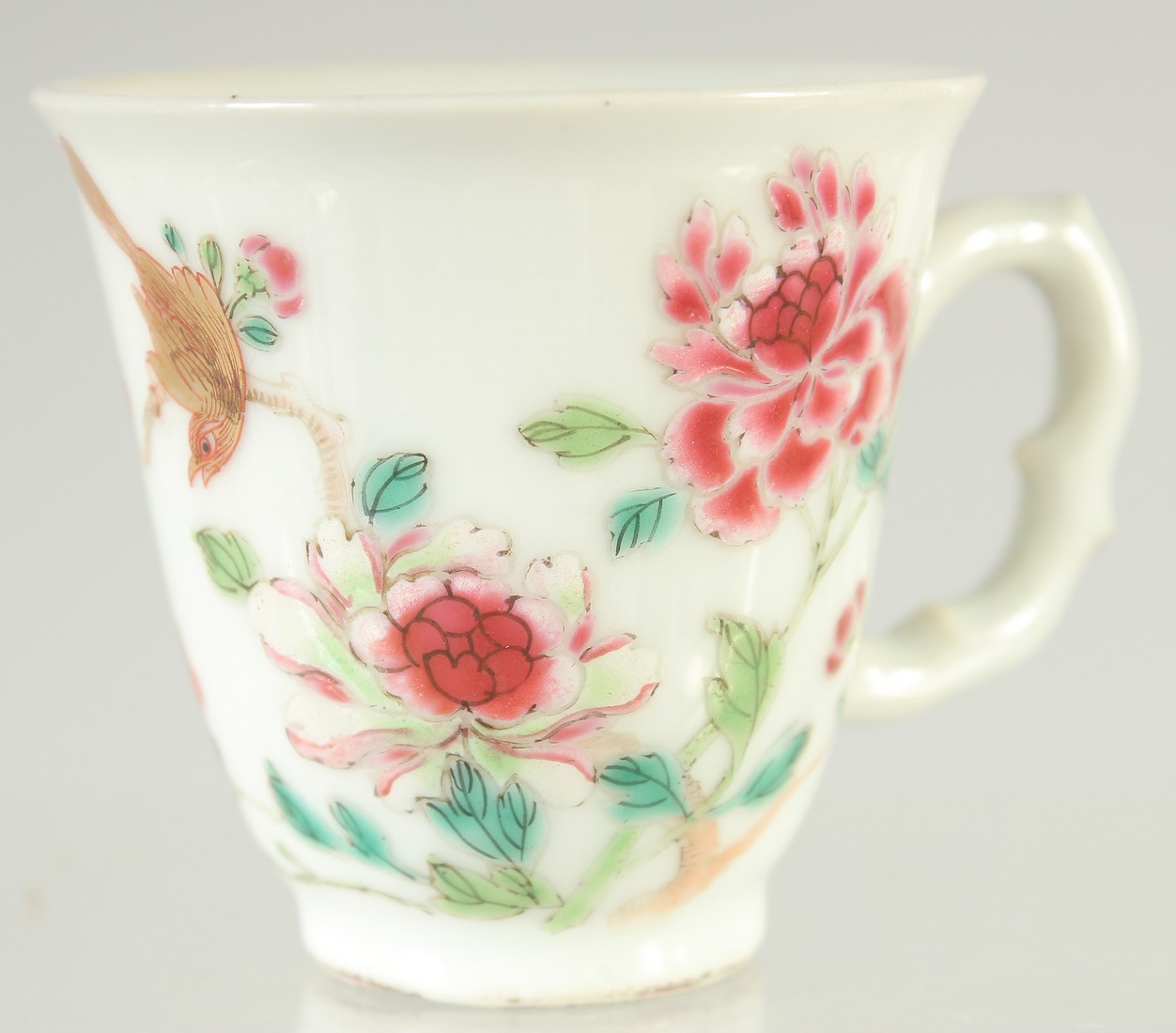 A 19TH CENTURY CHINESE FAMILLE ROSE PORCELAIN TEACUP, painted with a bird and flora, 6cm high.