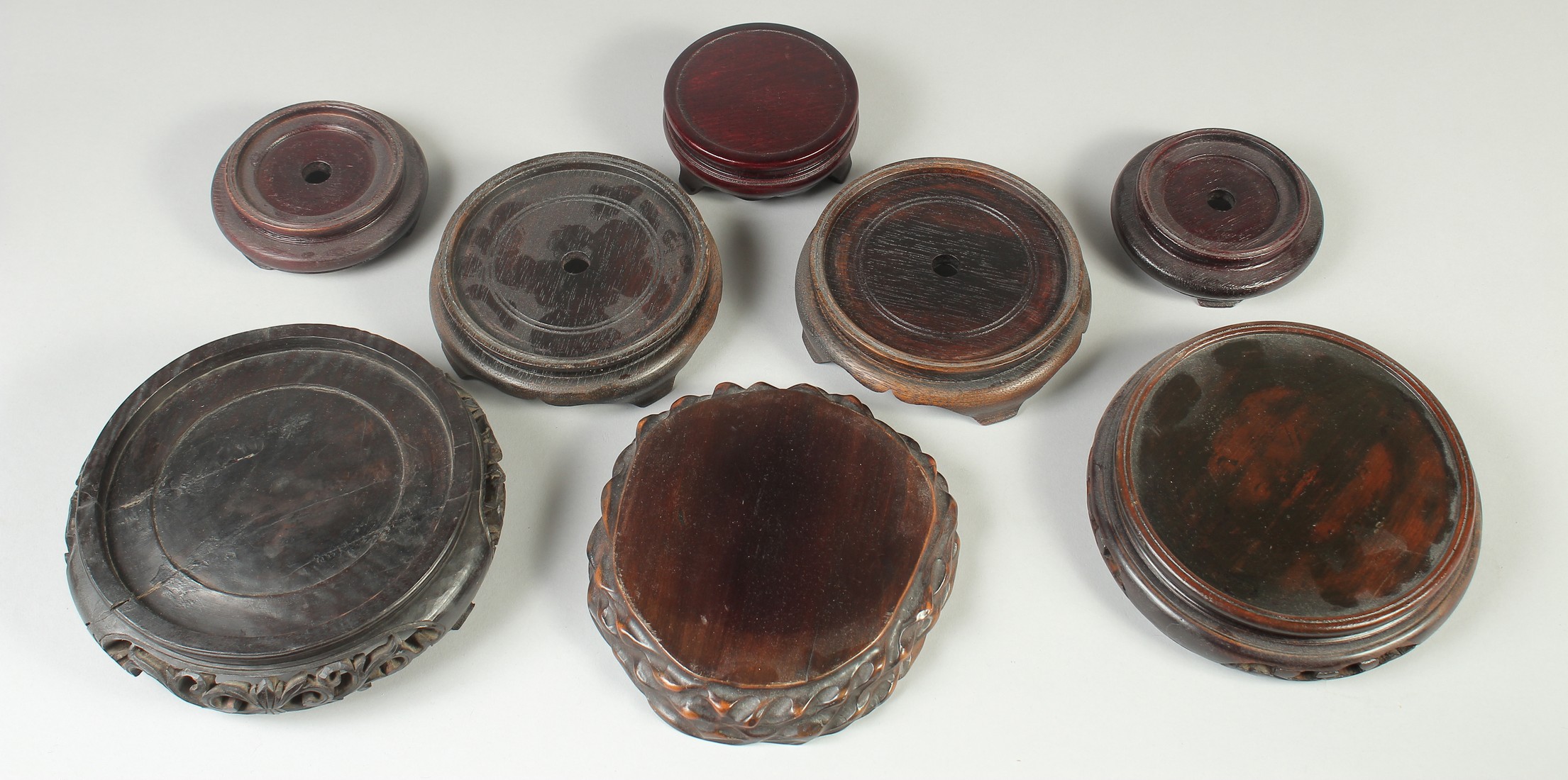A COLLECTION OF EIGHT CHINESE HARDWOOD STANDS, various sizes, largest 17.5cm diameter.