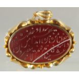 A FINE ISLAMIC CALLIGRAPHIC RED STONE SEAL inset within a gilt metal pendant, stamped to the
