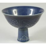 A CHINESE BLUE GROUND CIRCULAR STEM CUP with dragons in relief. Mark in blue.