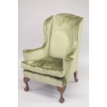 A GEORGIAN MANNER MAHOGANY FRAMED WING ARM CHAIR on cabriole legs with claw and ball feet.