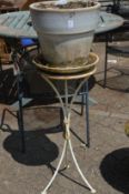 A glazed plant pot with wrought iron stand.