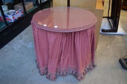 A cloth covered circular dressing table.