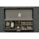 A watch box containing various coins.