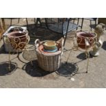 A pair of wrought iron plant pot stands, wicker basket and various plant pots.