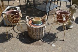 A pair of wrought iron plant pot stands, wicker basket and various plant pots.