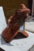 A terracotta garden ornament modelled as a ridge tile with a witch seated on top.