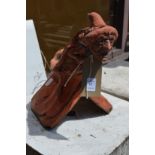 A terracotta garden ornament modelled as a ridge tile with a witch seated on top.