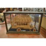 A wooden model of a Omnibus housed in a display case.