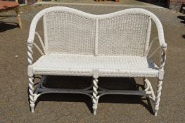 A white painted wicker two seater settee.