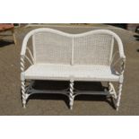 A white painted wicker two seater settee.