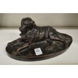 A bronze effect model of a reclining dog.