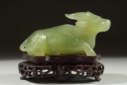 A CARVED JADE FIGURE OF A BULL on a fitted wooden stand, 11cm long.