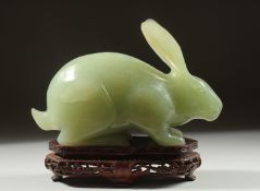 A LARGE CARVED JADE FIGURE OF A RABBIT on a fitted wooden base, 16cm long.