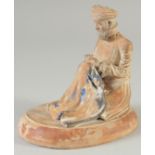 AN OTTOMAN TERRACOTTA SEATED FIGURE, on oval base, 14cm long.