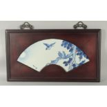 A CHINESE BLUE AND WHITE PORCELAIN PANEL, inset within a hardwood frame with fan shape border, the