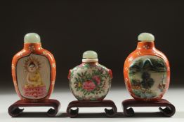 THREE CHINESE SNUFF BOTTLES AND STOPPERS with wooden stands, (3).