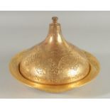 AN OTTOMAN TURKISH GILDED COPPER LIDDED DISH, with engraved foliate motifs, 23cm diameter.