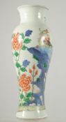 A CHINESE WUCAI PORCELAIN BALUSTER VASE, painted with an exotic bird on a rocky mound and native