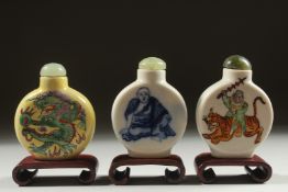 THREE CHINESE SNUFF BOTTLES AND STOPPERS with wooden stands, (3).