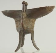 A CHINESE BRONZE CEREMONIAL RITUAL JUE CUP, on tripod legs, 15.5cm high.