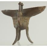 A CHINESE BRONZE CEREMONIAL RITUAL JUE CUP, on tripod legs, 15.5cm high.