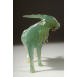 A CARVED JADE FIGURE OF A GOAT on a wooden stand, 12cm long.