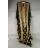 AN ARAB LADIES BLACK SATIN AND GOLD THREAD DECORATED DRESS.