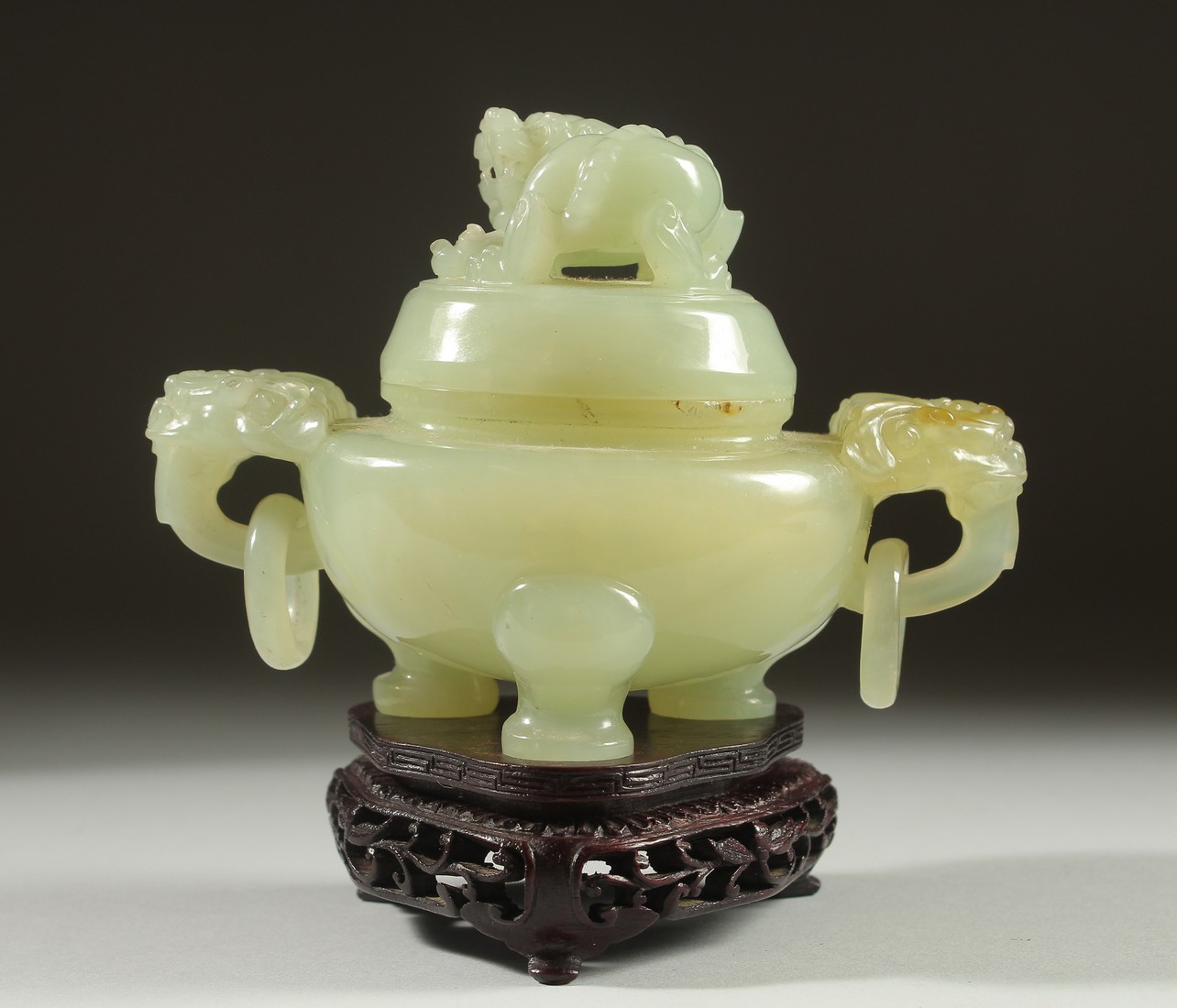 A CARVED JADE KORO AND COVER on a fitted wooden stand, with drop ring twin handles and carved foo