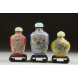THREE CHINESE REVERSE GLASS PAINTED SNUFF BOTTLES, with wooden stands, each finely painted with