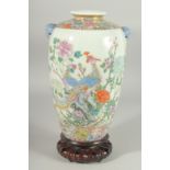 A CHINESE FAMILLE ROSE PORCELAIN VASE on hardwood stand, painted with exotic birds and native flora,