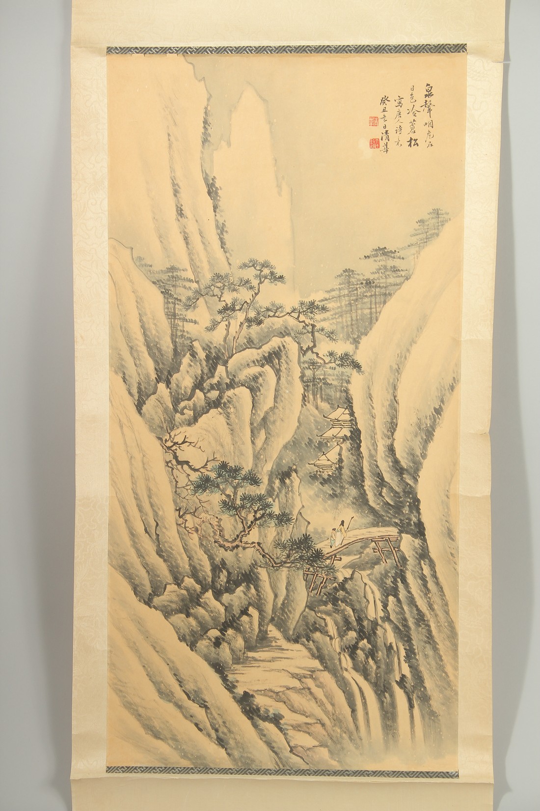 A CHINESE WATERCOLOUR PAINTING ON SILK SCROLL, depicting two figures approaching a temple in a