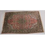A PERSIAN PART SILK CARPET pink ground with sylised floral decoration within a similarly border.