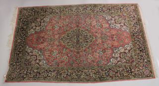 A PERSIAN PART SILK CARPET pink ground with sylised floral decoration within a similarly border.