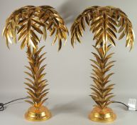 A PAIR OF GILT METAL PALM TREE LAMPS on circular bases. 25ins high.
