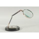 A CHROME MAGNIFYING GLASS on an oval base.
